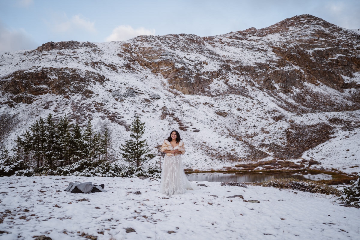 Bride in a gown with fur shawl in a snowy mountain landscape