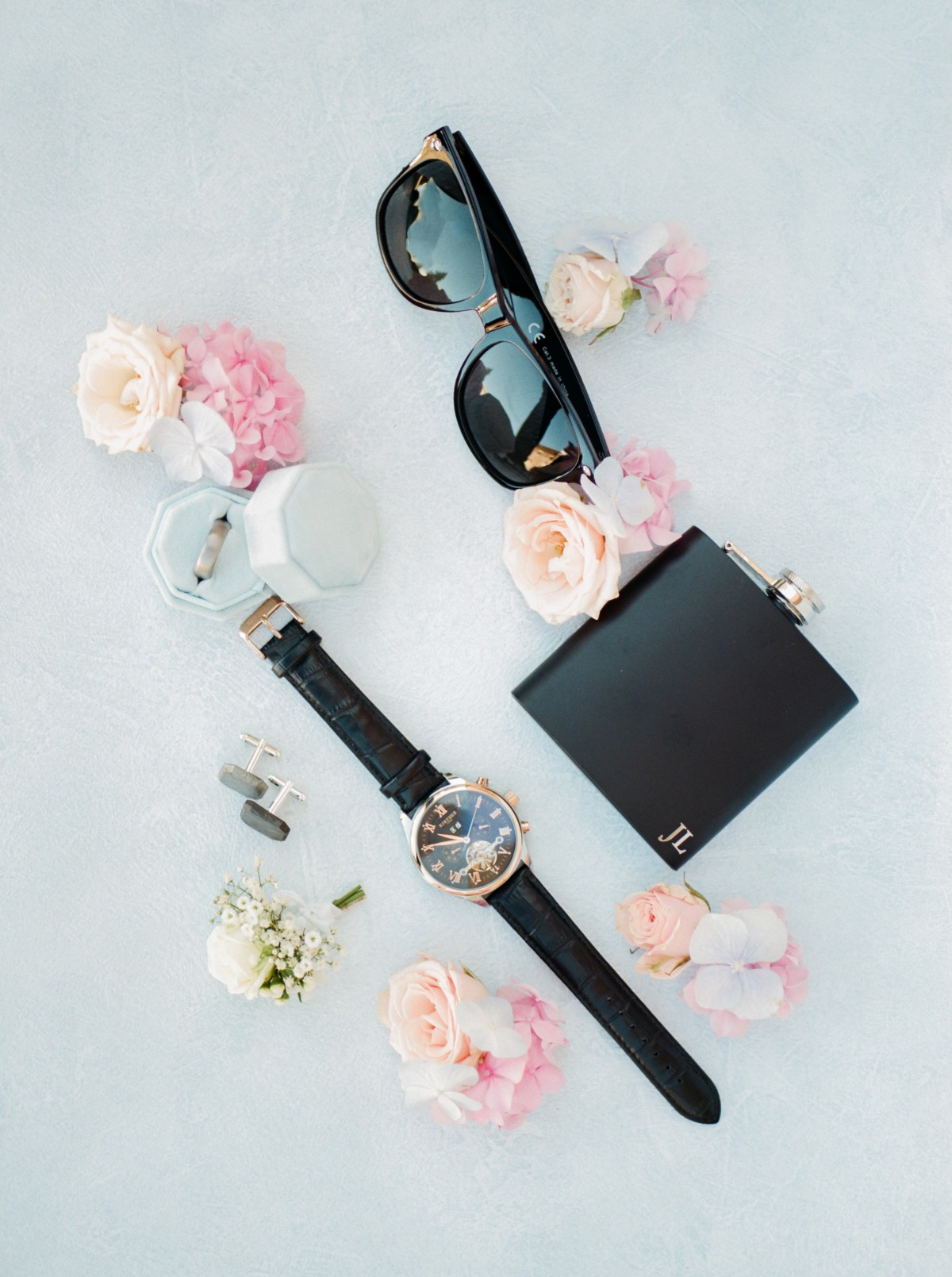 Wedding accessories arranged with flowers on a light background