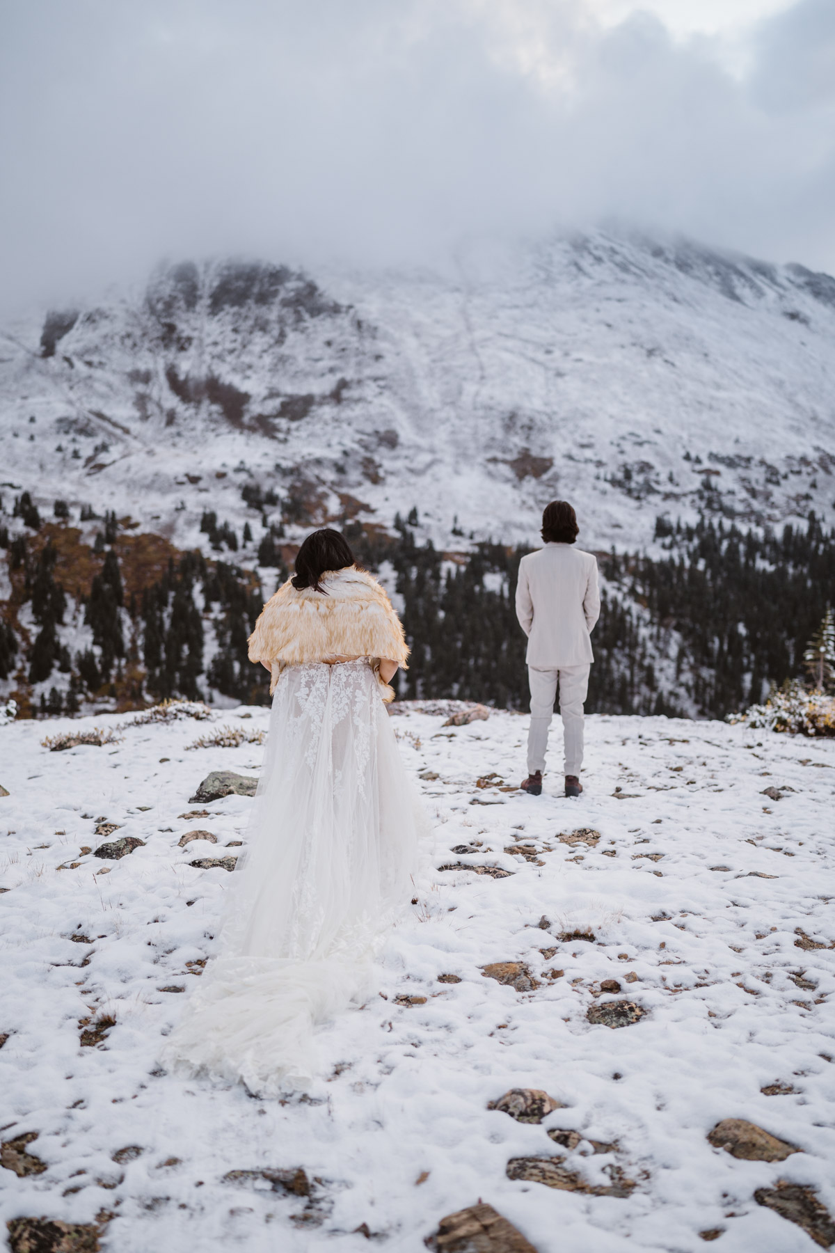Bride and groom in a snowy mountain location facing each other