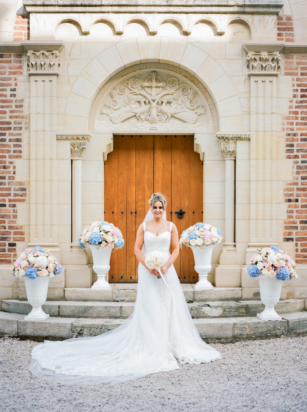 Bride in wedding dress poses in front of church entrance