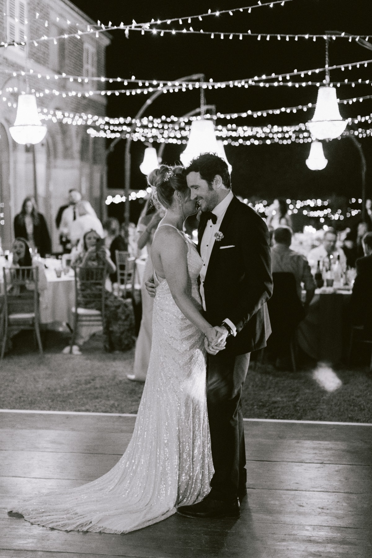 Elegant couple dances at a wedding under string lights
