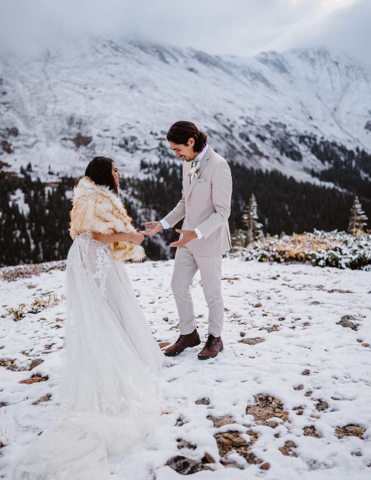 Couple in wedding attire celebrating in the snowy mountains