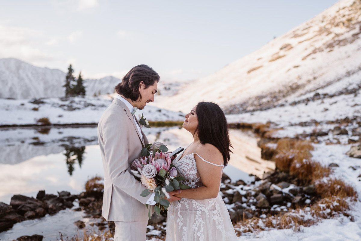 Bride and groom look lovingly at each other during snowy wedding ceremony