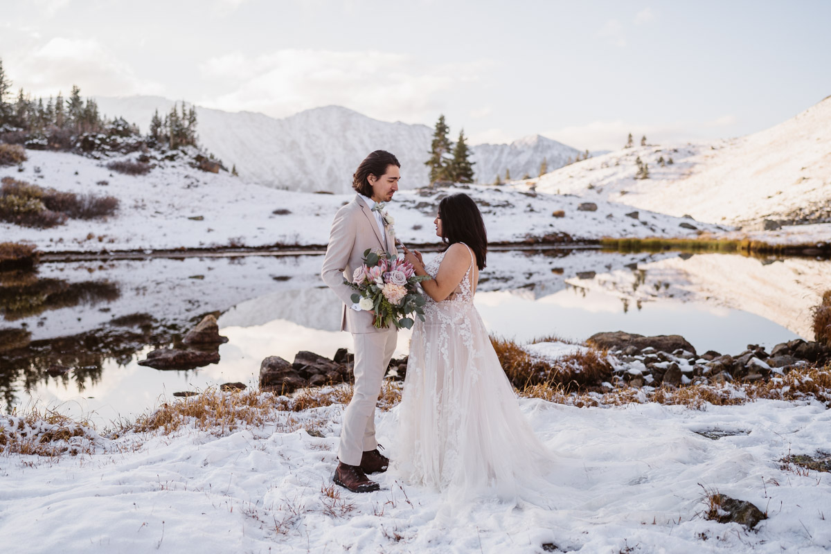 Wedding couple embraces on snowy mountain lake shore