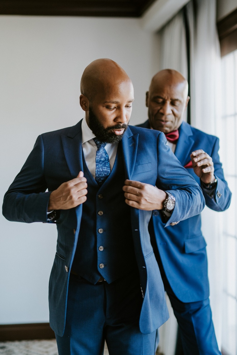 Groom in blue suit getting help from his father for wedding