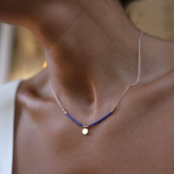 Elegant woman wearing a gold necklace with a blue stone
