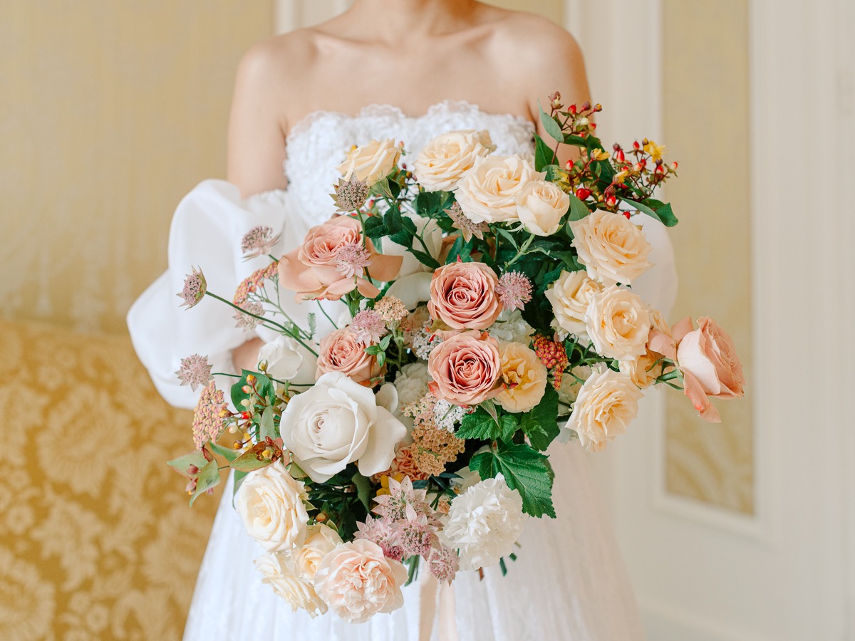 Bride holding a beautiful bouquet of roses and flowers in a white dress