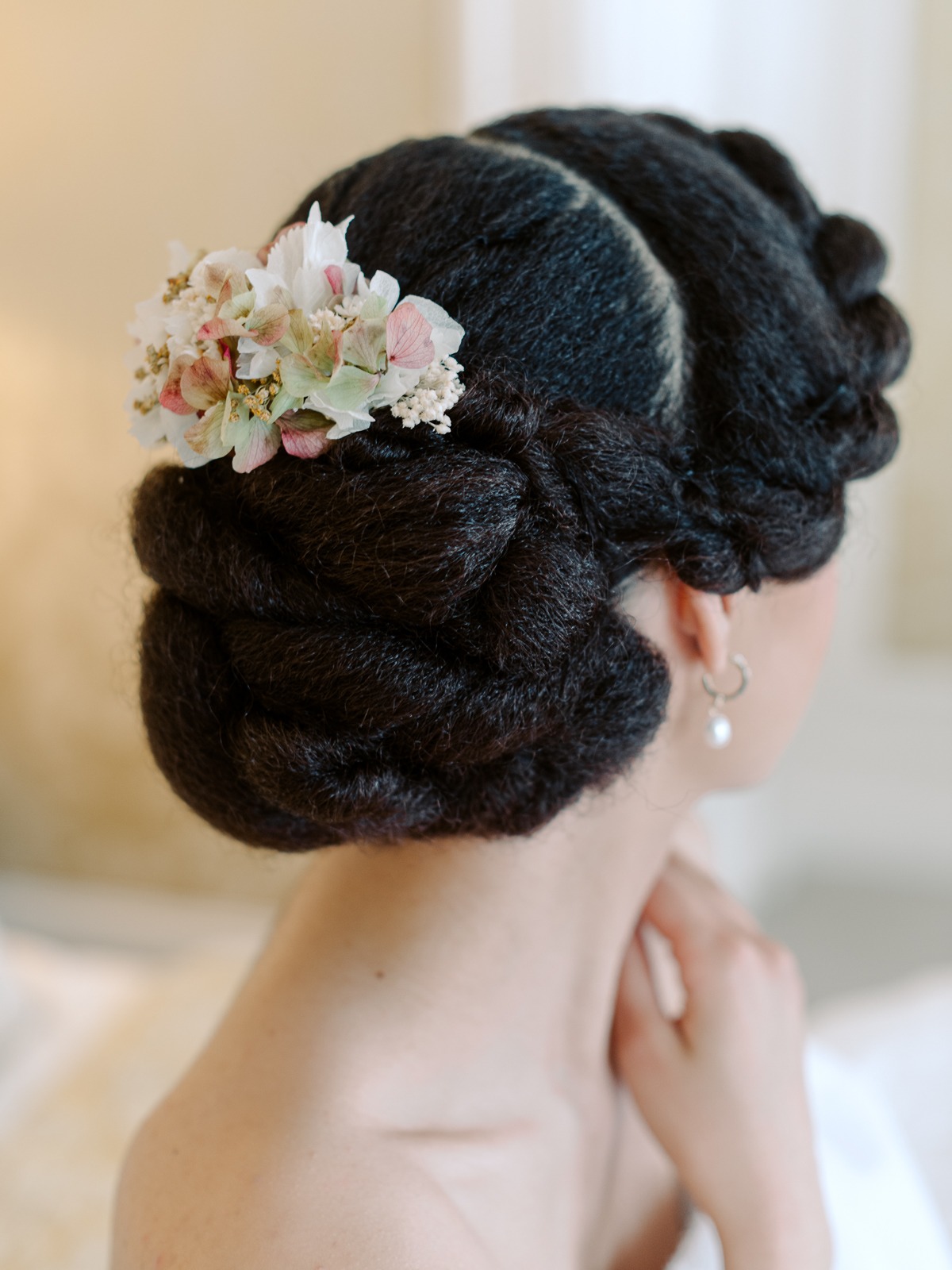 Elegant hairstyle with floral accents and pearl earrings