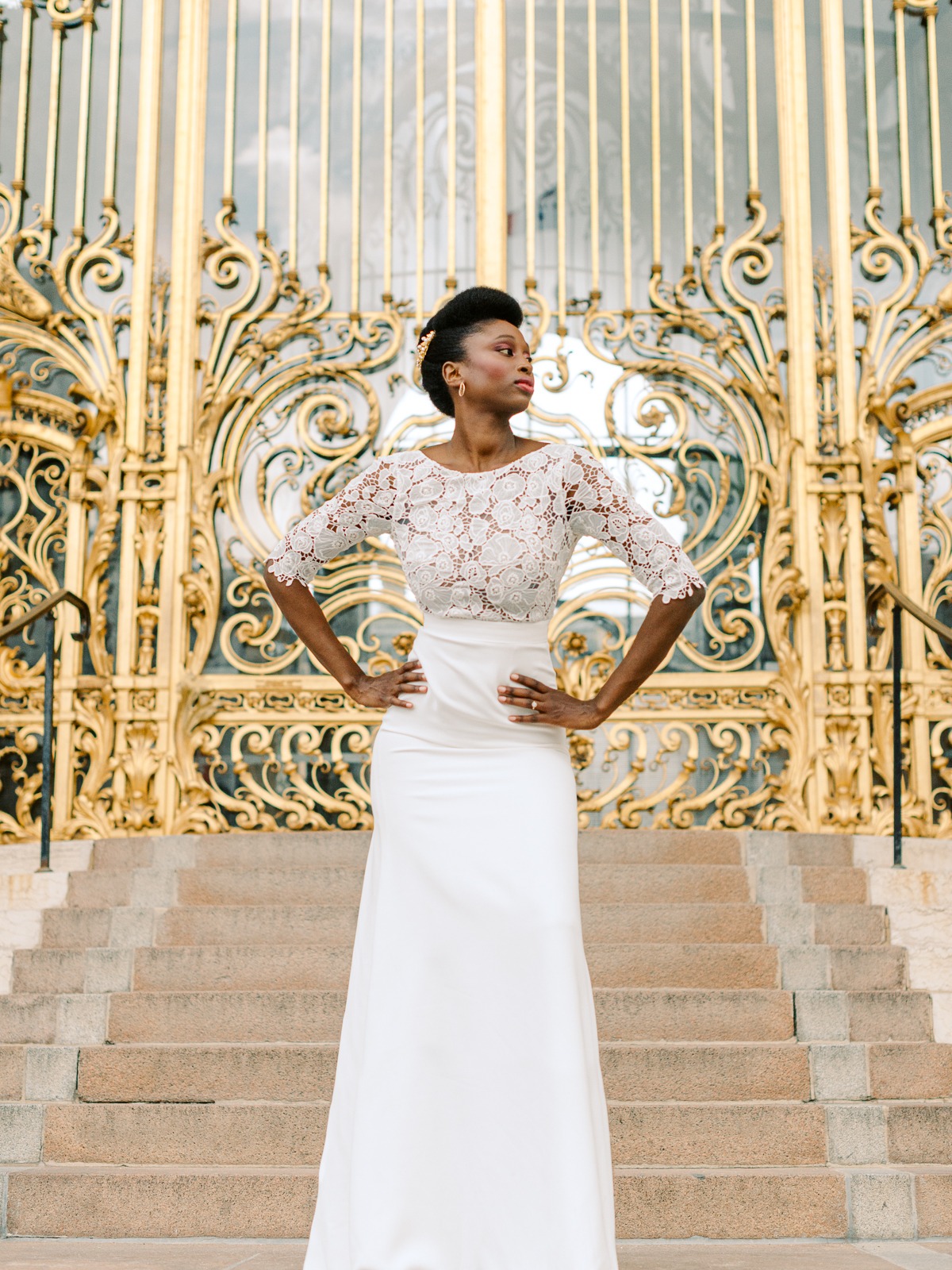 Elegant bride in a white gown poses in front of a golden gate