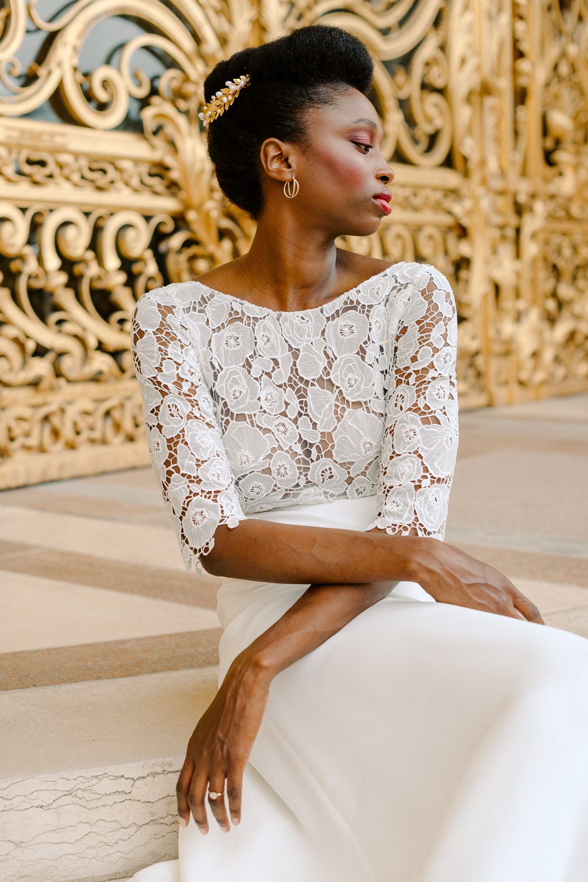 Elegant bride in a lace top looks at a golden structure