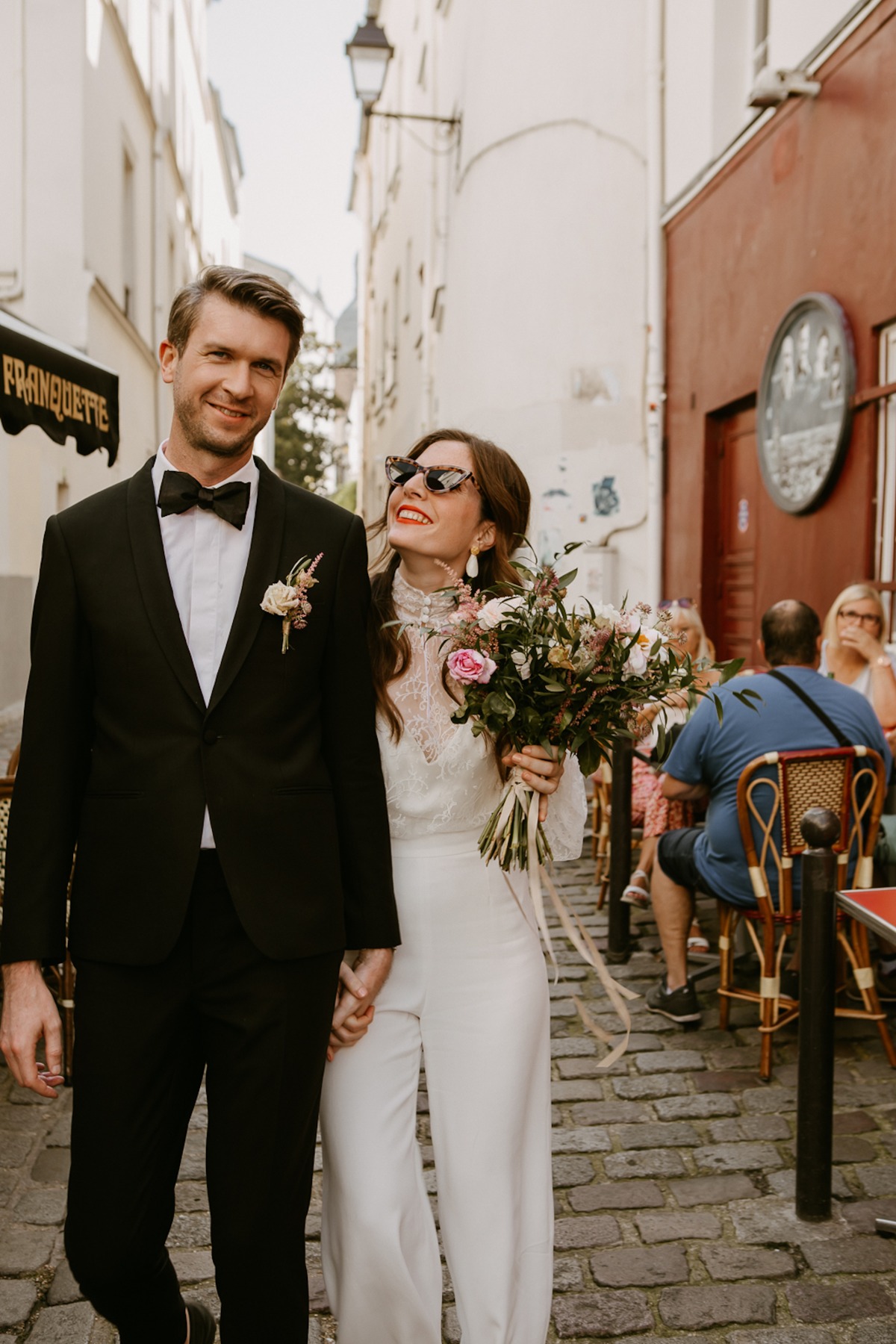 Newlyweds walking down a cobbled street, smiling happily on their wedding day