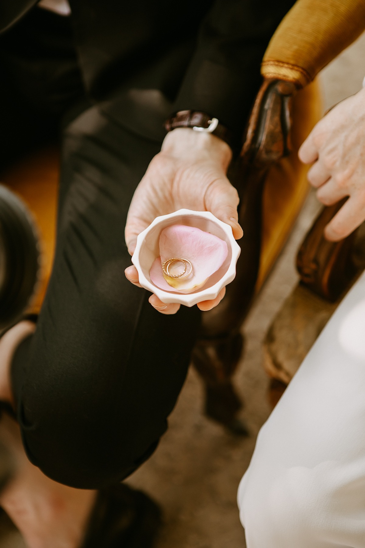 Wedding rings in a small bowl with pink petals, close-up shot