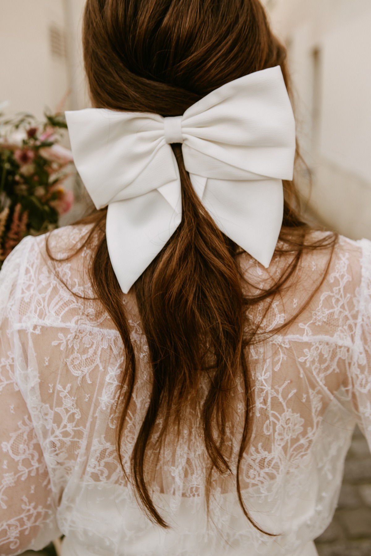 Bride with a large white bow in her hair, lace dress back view