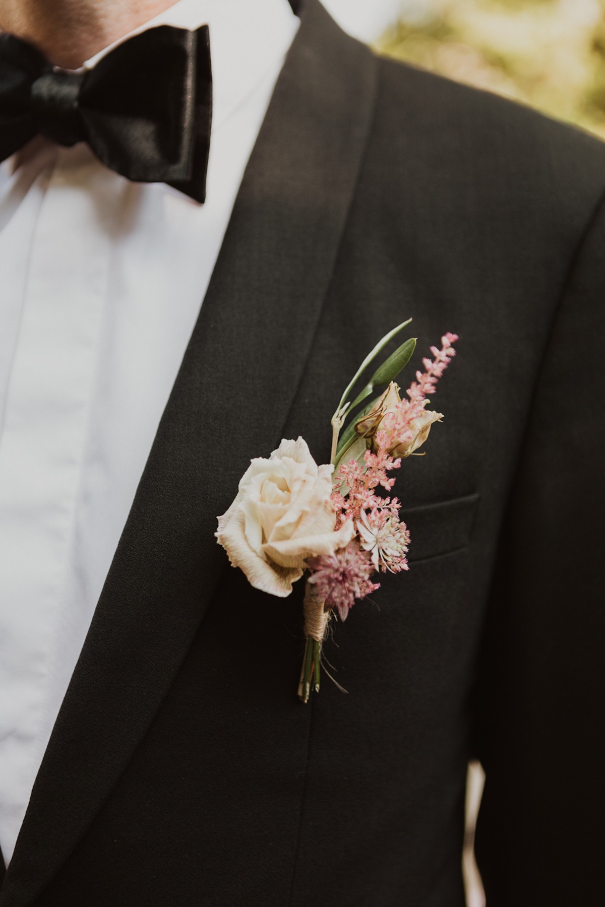 Groom in a black suit with a boutonniere flower and bow tie