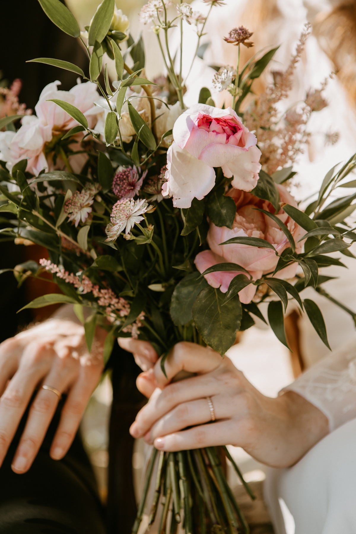 Bride and groom holding wedding bouquet with rings