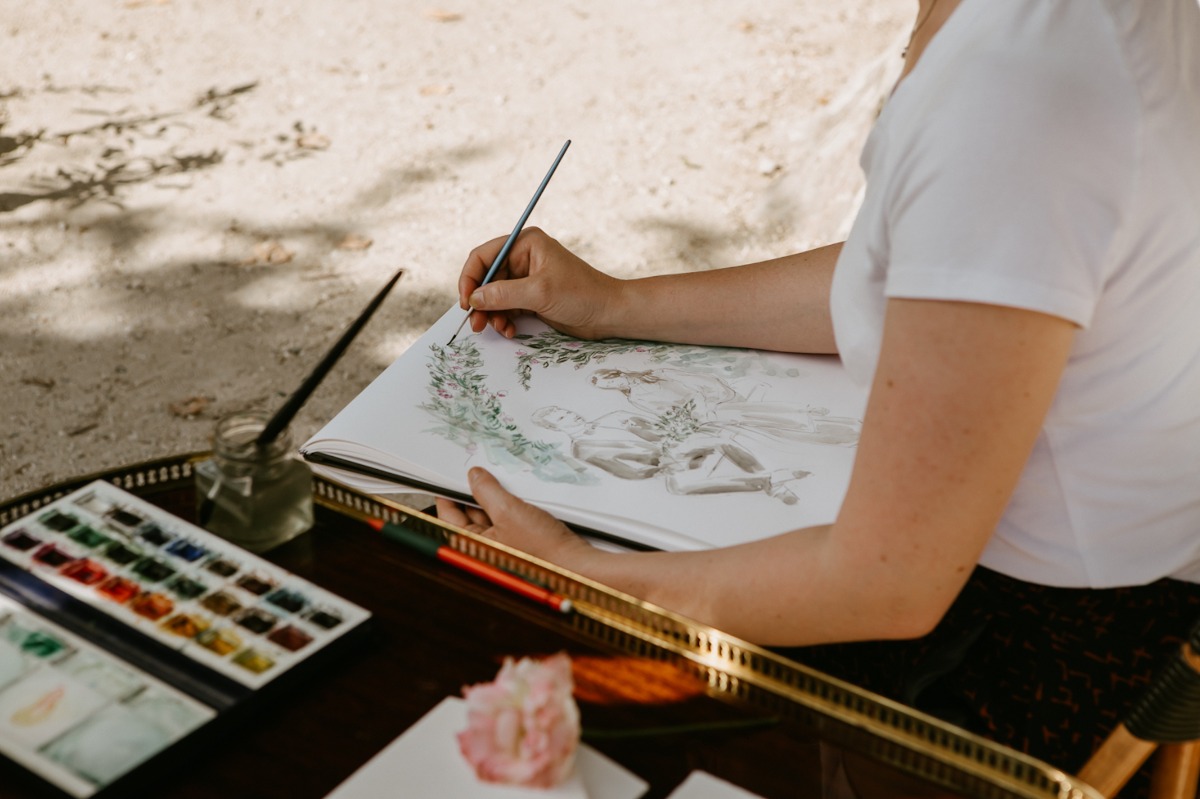 Artist painting watercolor illustration outdoors with brush and paints