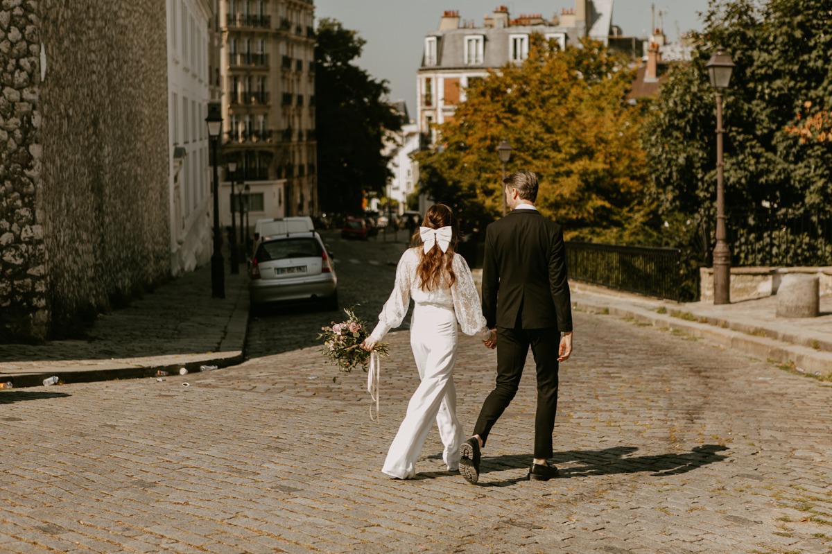 Newlyweds strolling down a cobblestone street in Paris after wedding