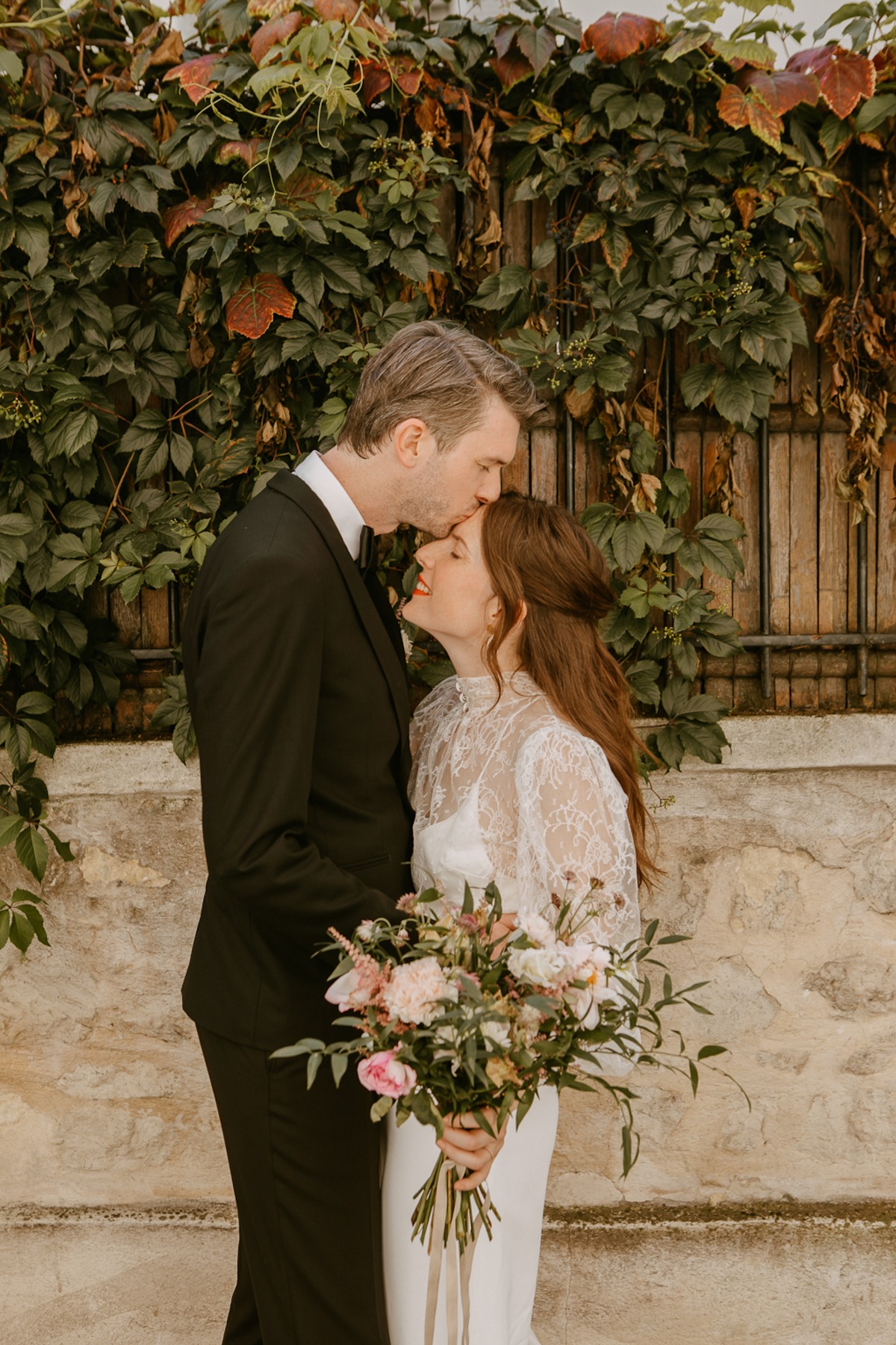 Wedding couple shares a tender moment with a kiss on the forehead