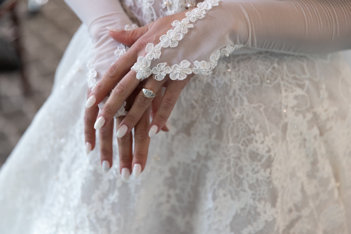 Elegant bride wearing white gloves and wedding dress close up