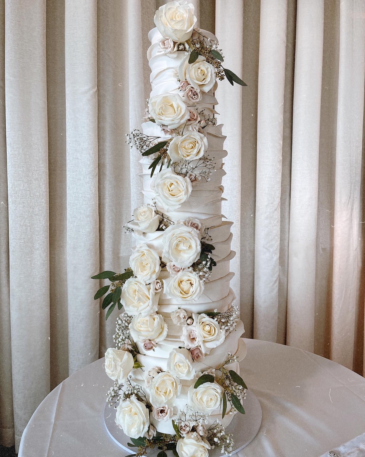Elegant tall wedding cake decorated with white roses