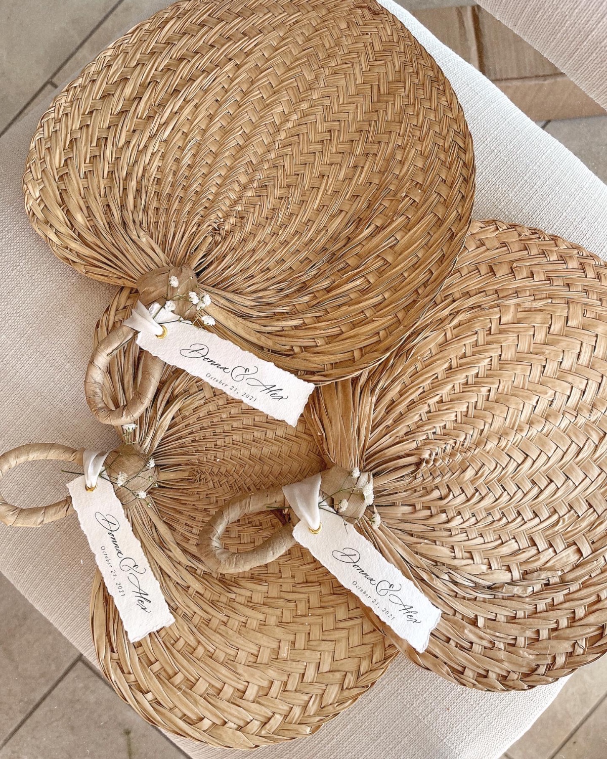 Handwoven wedding fans with personalized tags on a chair