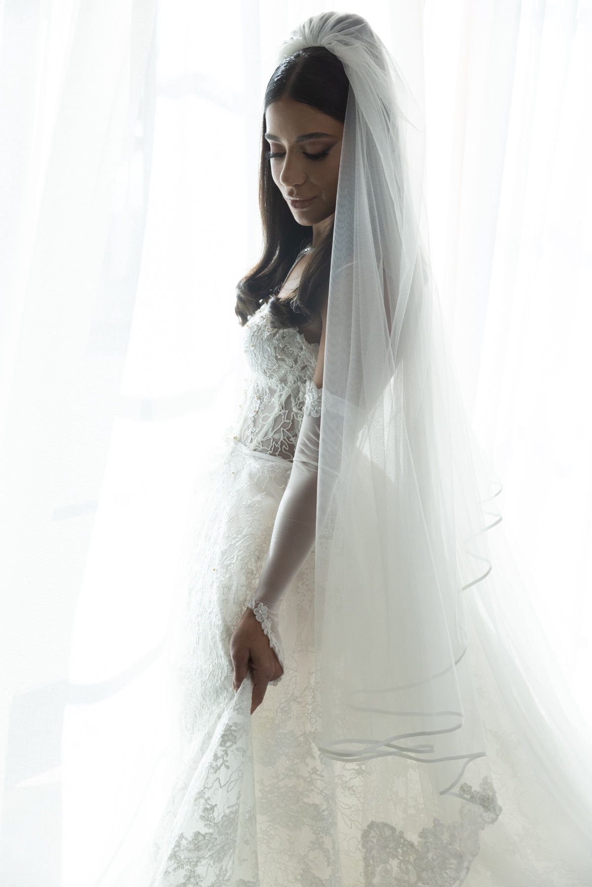 Elegant bride in a white wedding dress with veil in soft light
