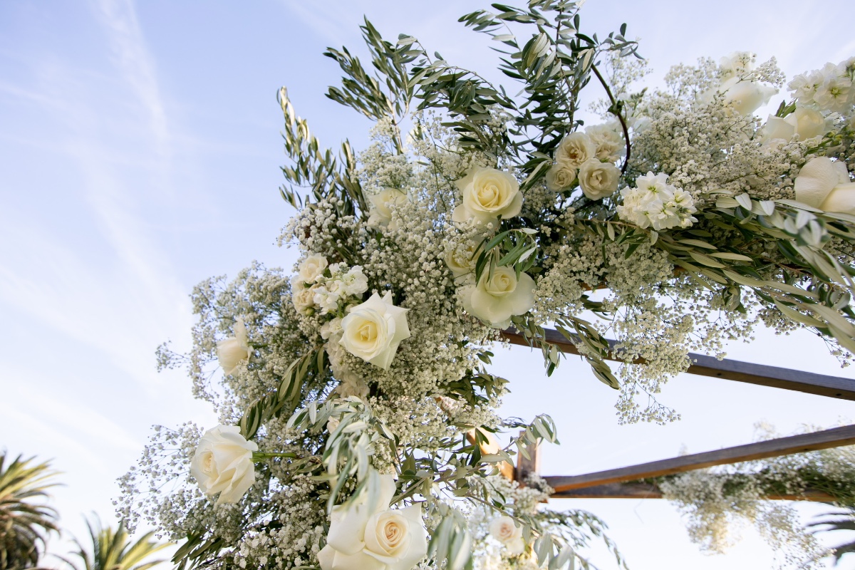 Wedding arch decorated with white roses and floral arrangement