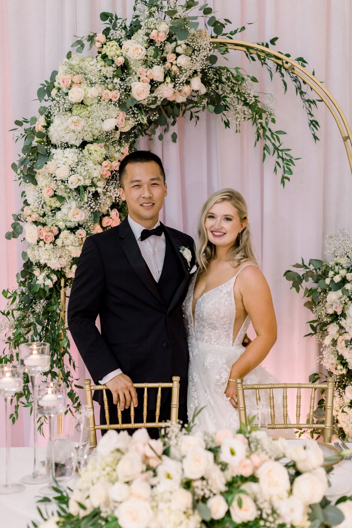 Happy couple poses at their elegant floral wedding reception
