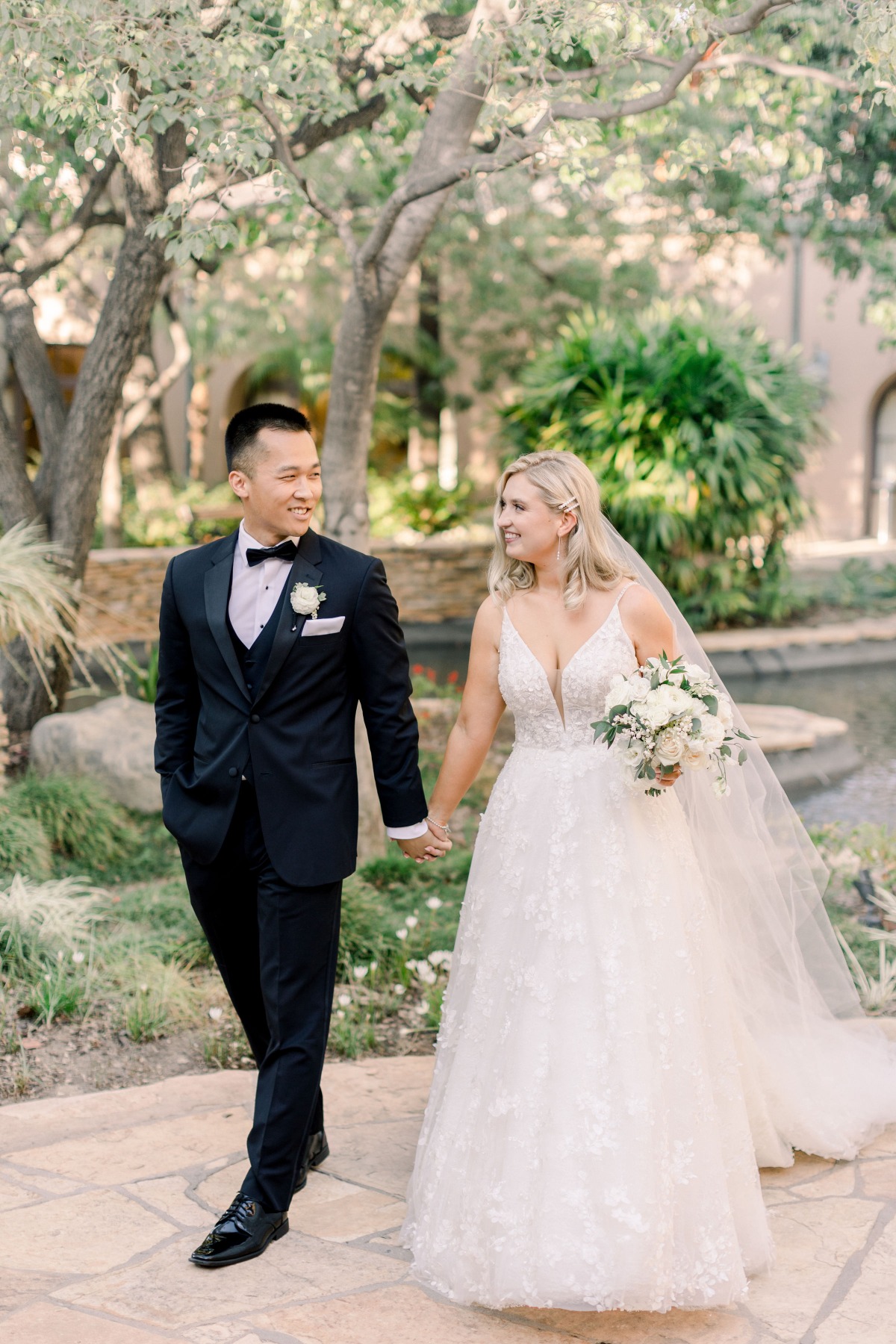 Happy wedding couple strolling hand in hand in garden
