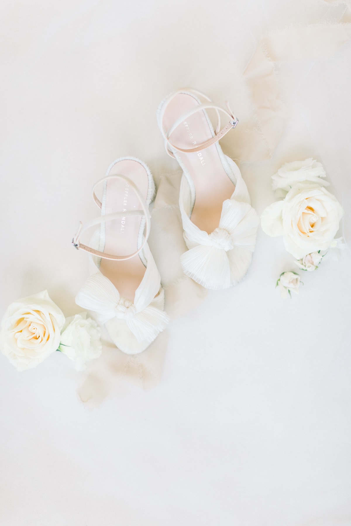 Elegant white wedding shoes with bow and floral details