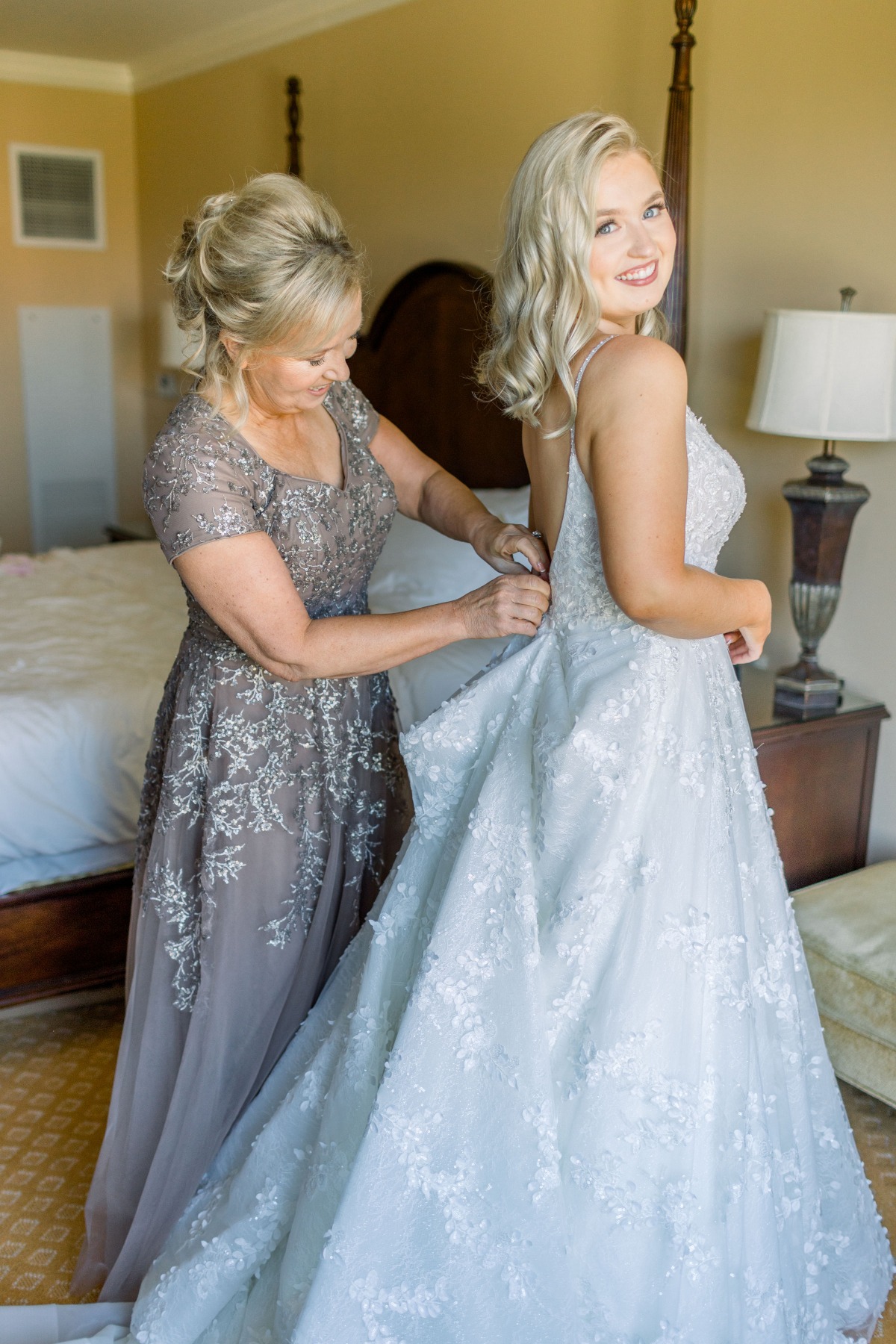 Mother helping bride into her beautiful wedding gown