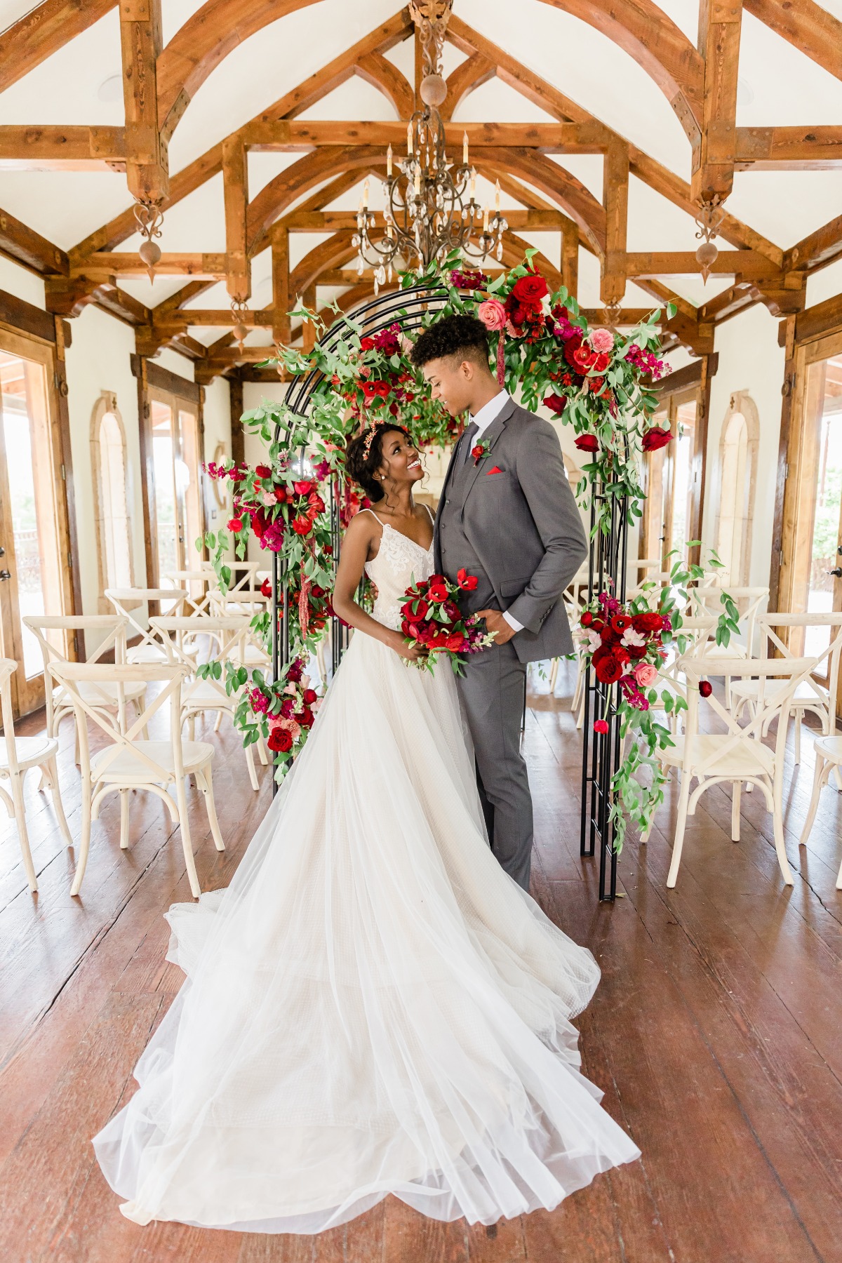 Elegant couple at a wedding ceremony with red floral decor