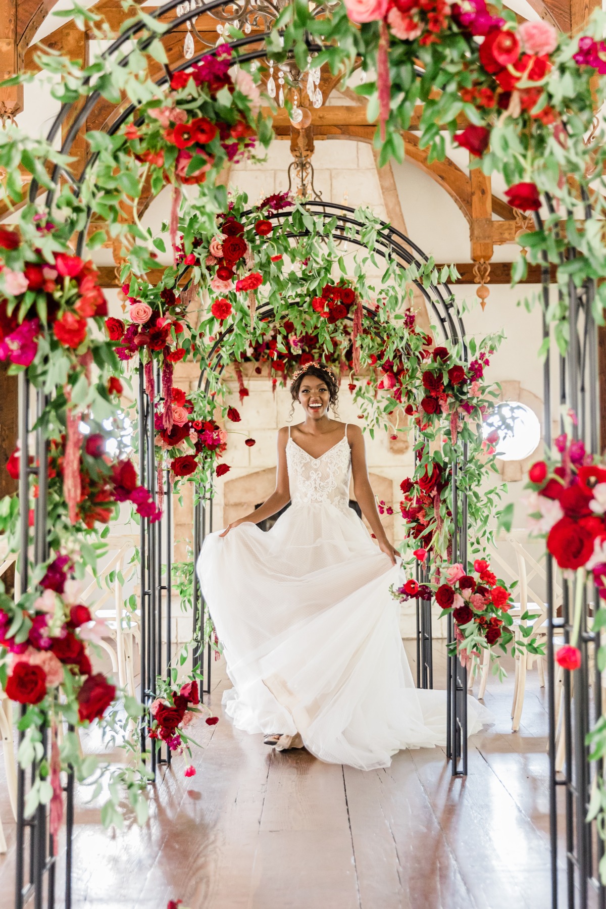 Smiling bride walks through floral archway, wedding venue