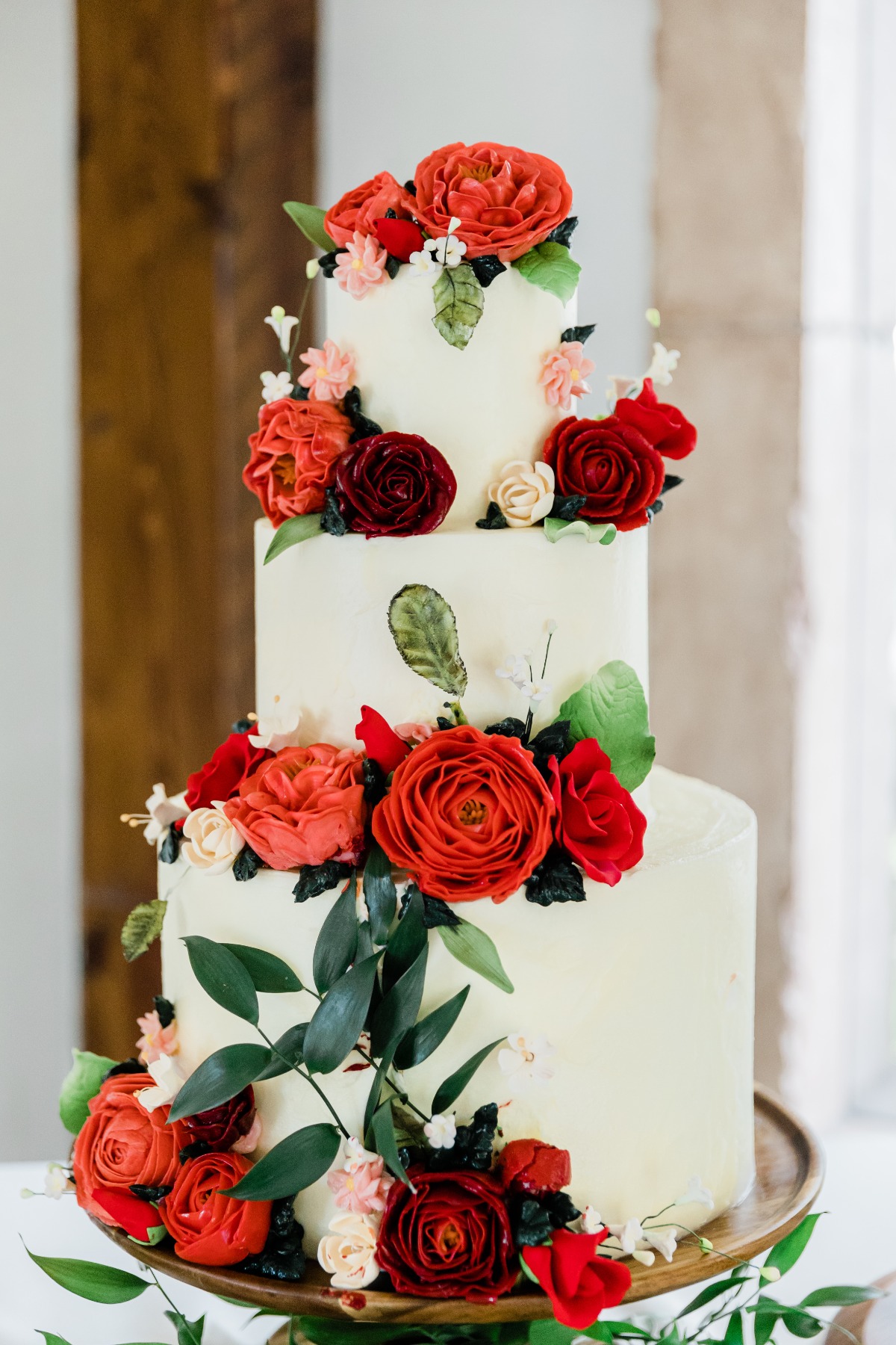 Elegant three-tiered wedding cake decorated with vibrant red roses