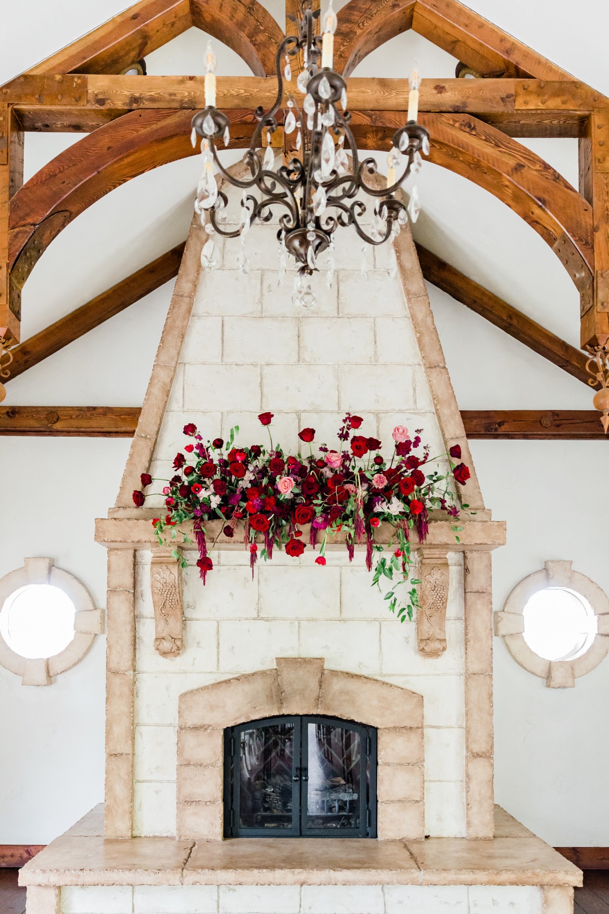 Elegant fireplace adorned with flowers under a chandelier