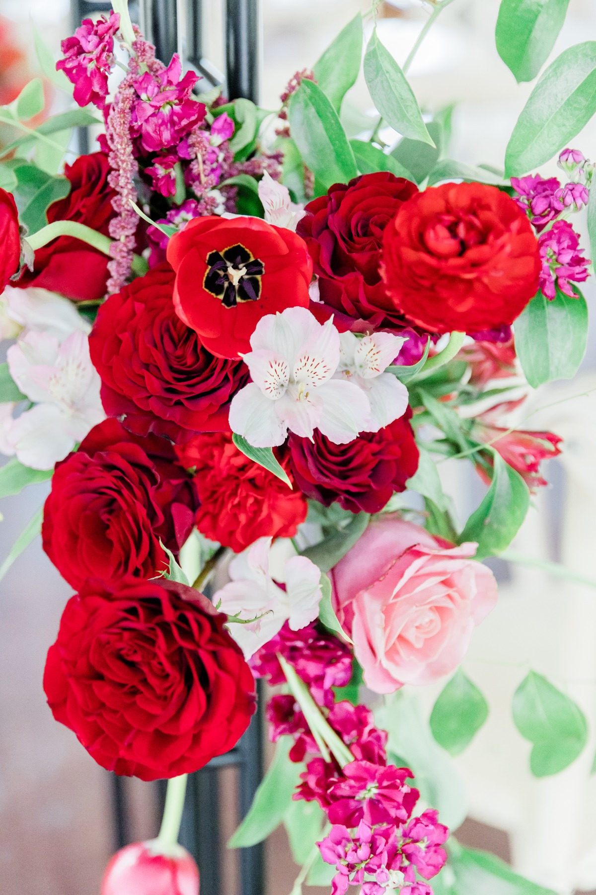 Vibrant red floral arrangement with roses, tulips, and greenery