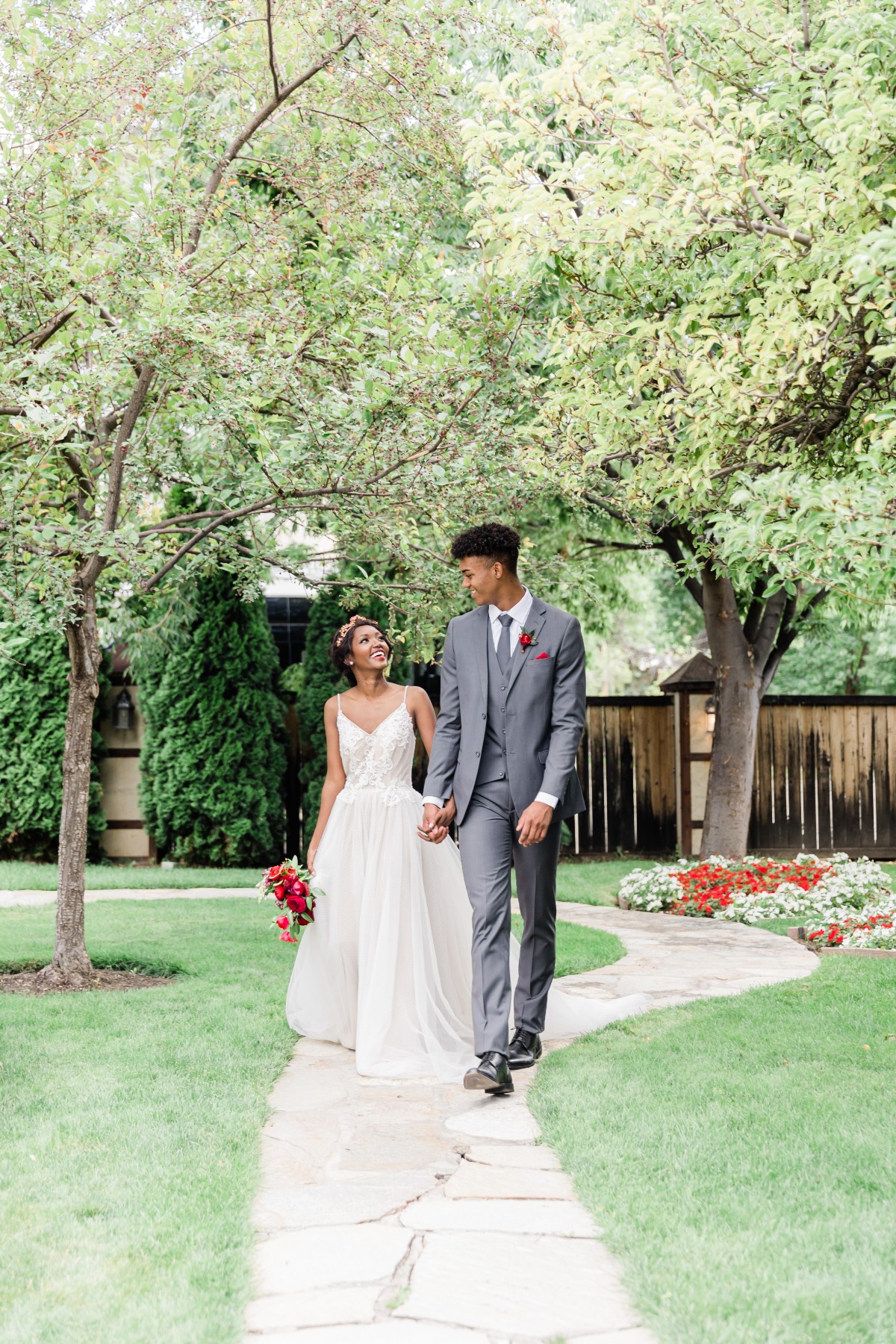 Happy newlywed couple walking on path through garden