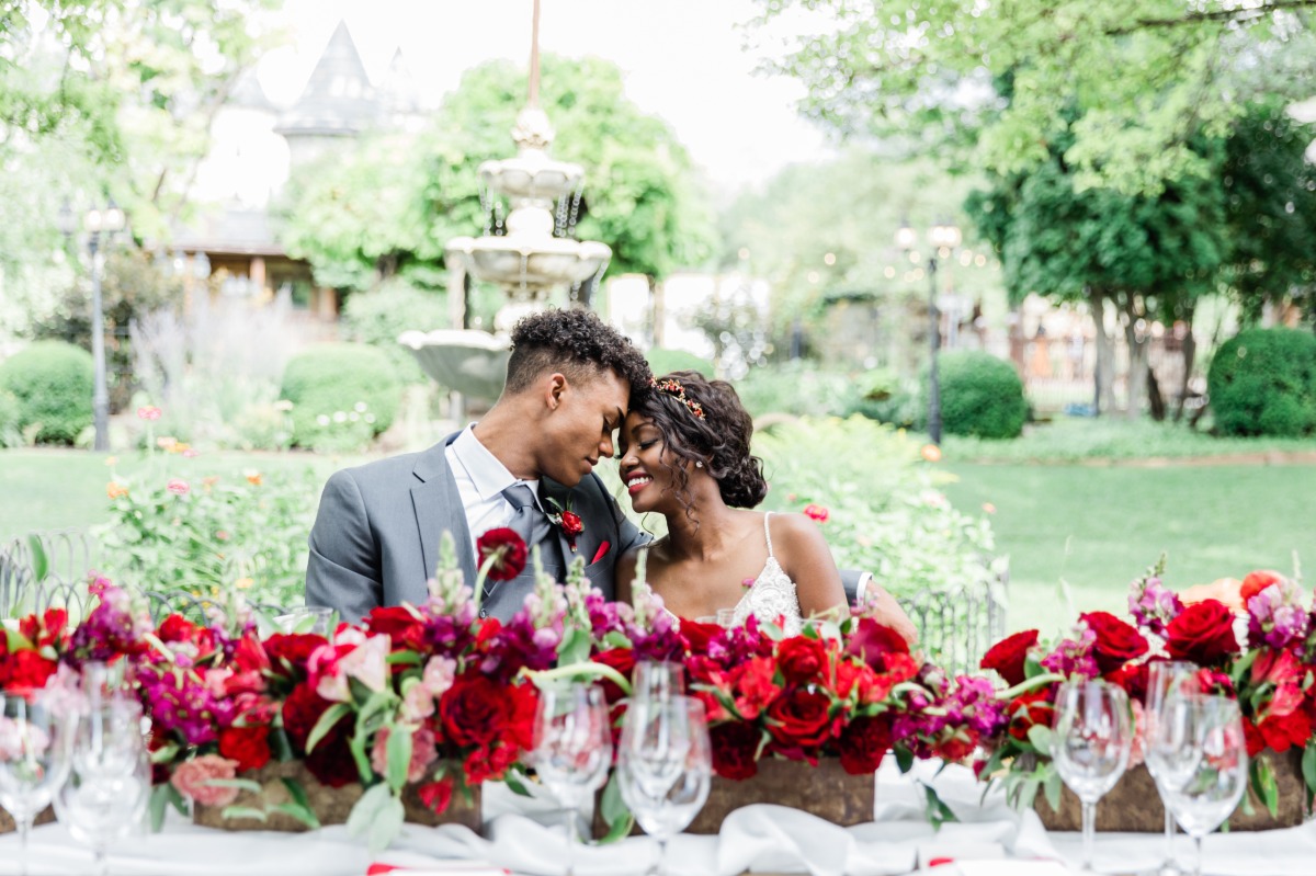 Romantic wedding couple with lush red floral table decor