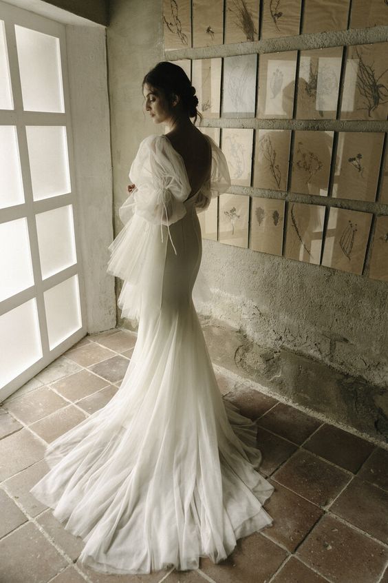 Elegant bride in a dreamy wedding dress, posing by a window