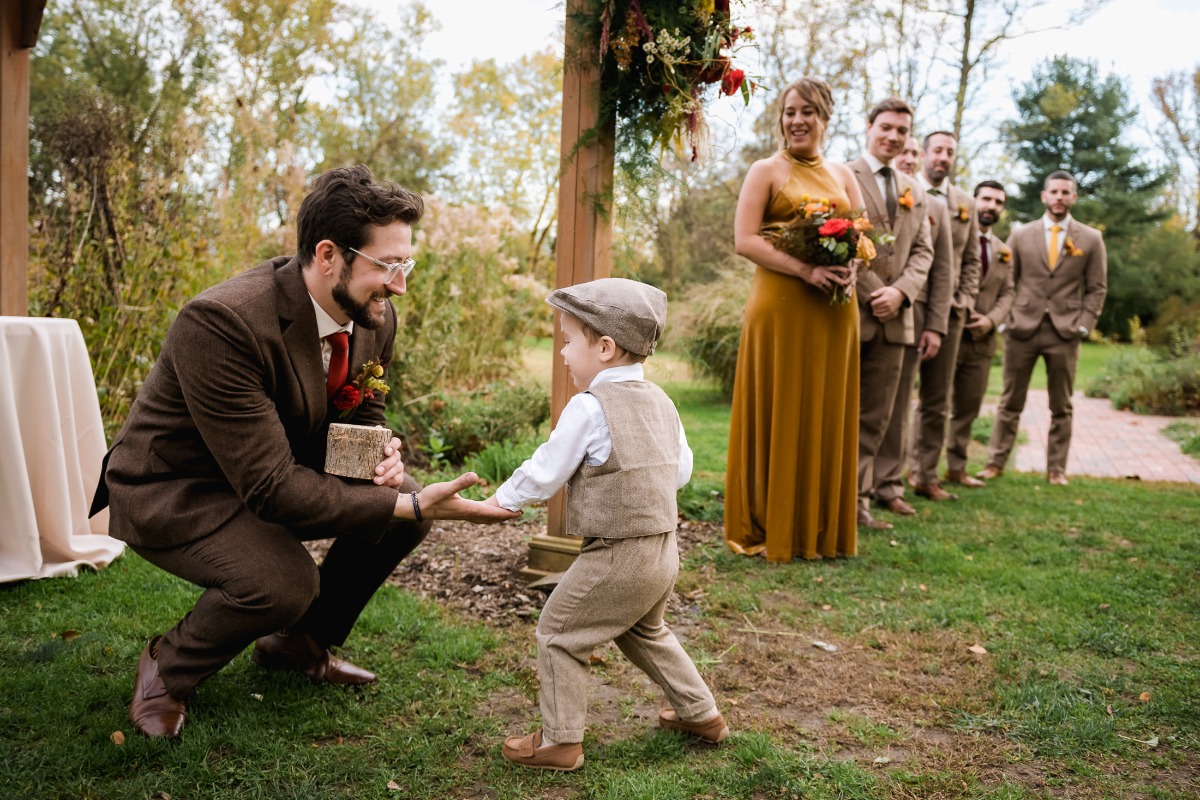 A joyful ring bearer and groomsman share a moment at an outdoor wedding