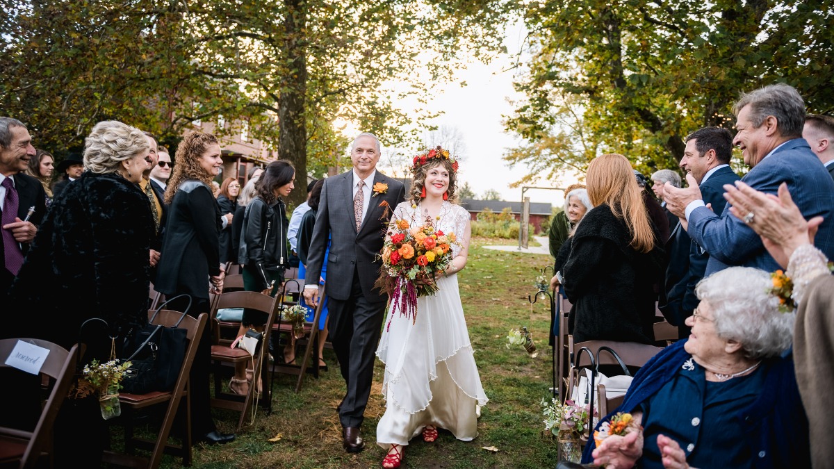 Bride walking down the aisle with her father at outdoor wedding