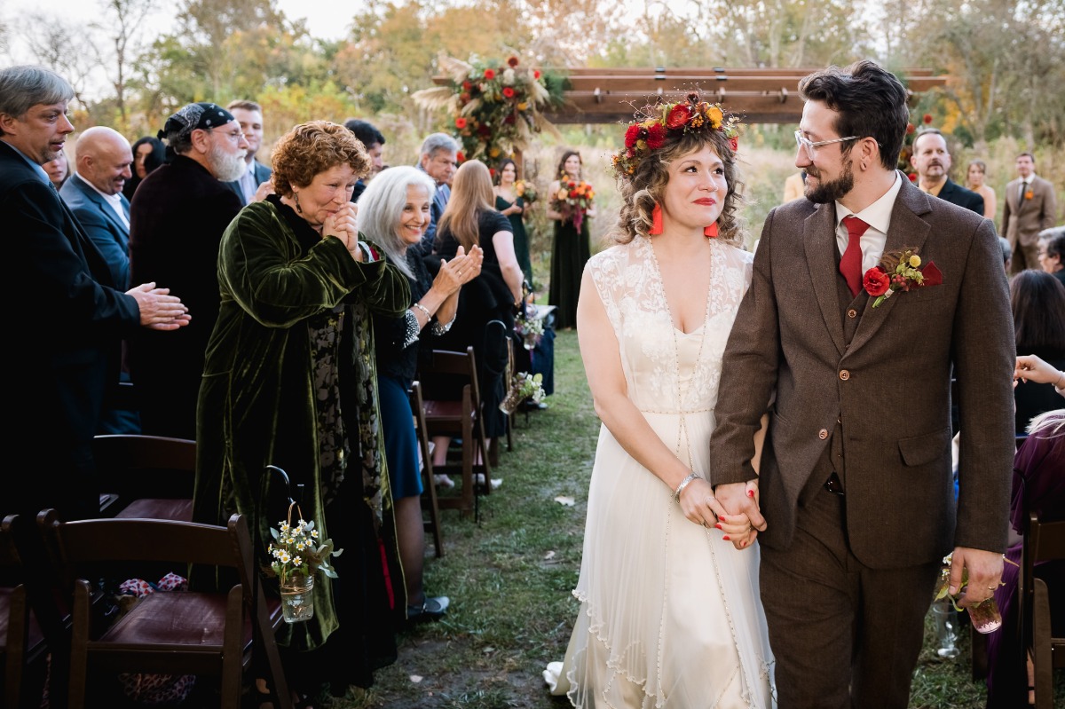 Newlyweds walk down the aisle with a wedding audience clapping