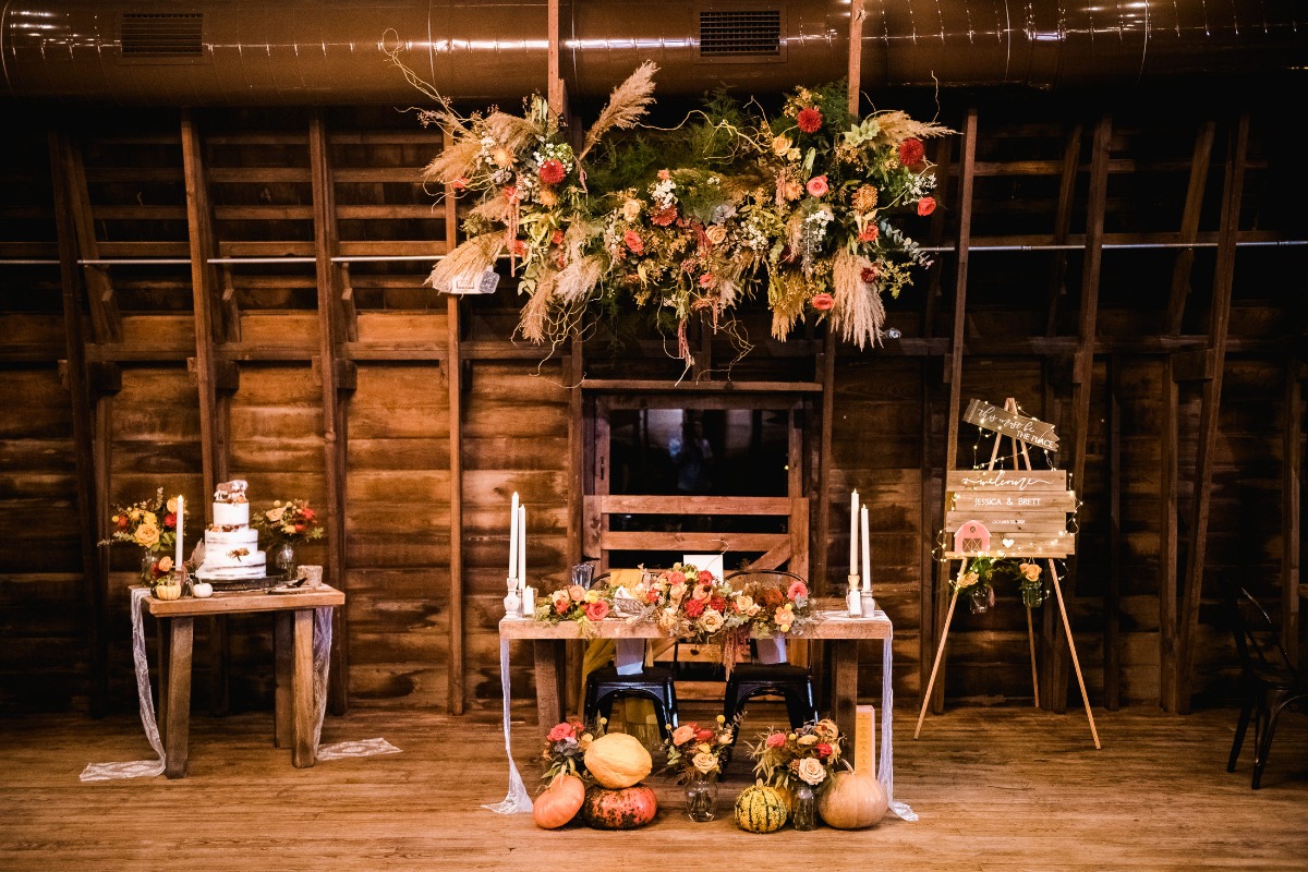 Rustic wedding reception setup with floral arrangements and pumpkins