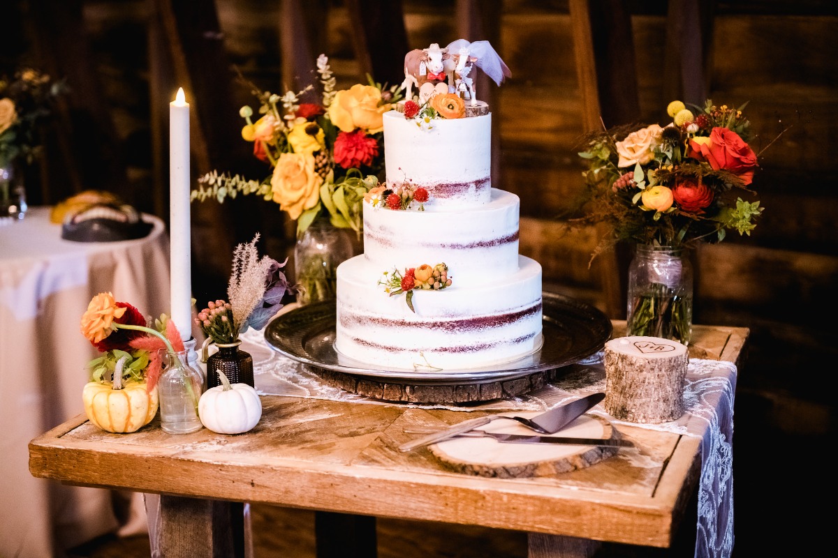 Rustic three-tiered wedding cake with flowers and pumpkin decor