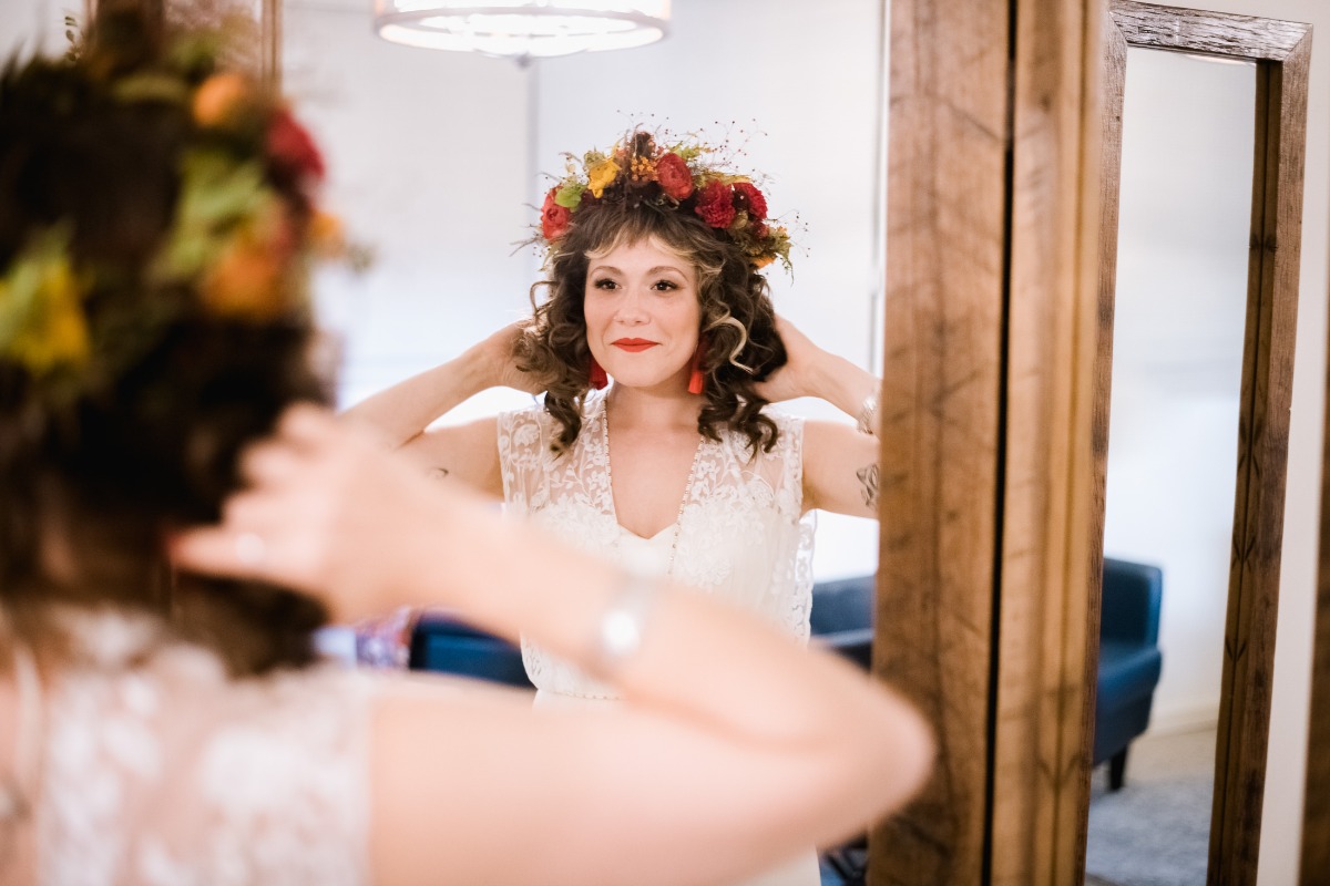 Bride in mirror wearing flower crown, preparing for wedding day