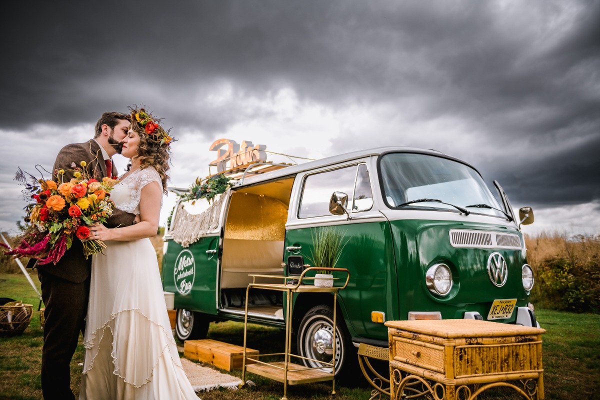 Wedding couple kisses beside a vintage green VW bus