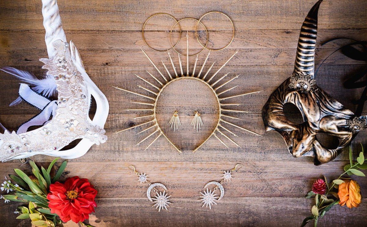 Elegant masks, earrings, and sunbursts on a rustic wooden surface