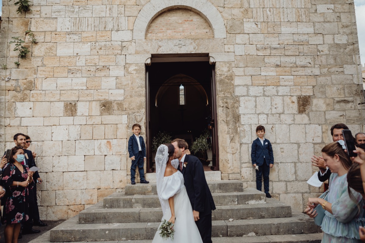 Newlyweds share a kiss after wedding ceremony in front of church