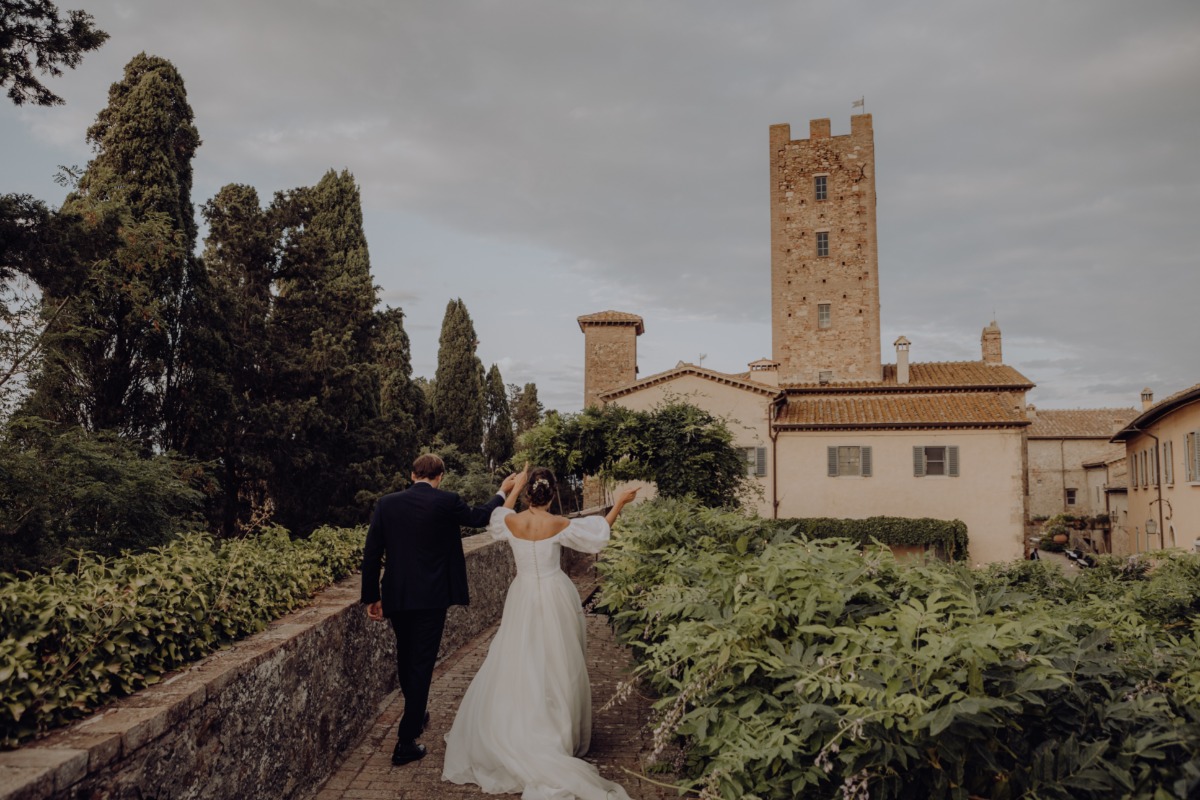 Newlyweds walk towards a historic tower on their wedding day