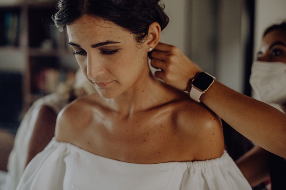 Bride having her earrings put on before the wedding